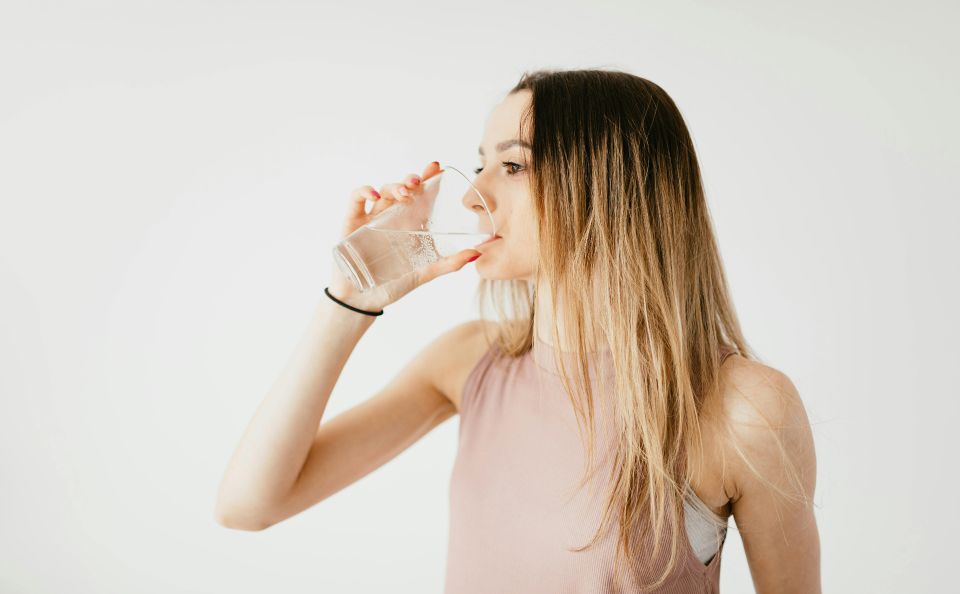 Junge Frau die aus einem Glas Wasser trinkt